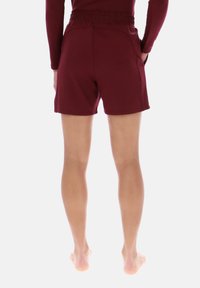 Bordeauxrode sportshorts met een elastische tailleband, voorzien van een gladde textuur en strakke lijnen. Ontworpen voor comfort en bewegingsvrijheid.