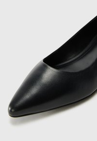 Escarpin noir en cuir avec un design à encolure basse. Texture lisse et légère brillance, présentant une esthétique minimaliste.