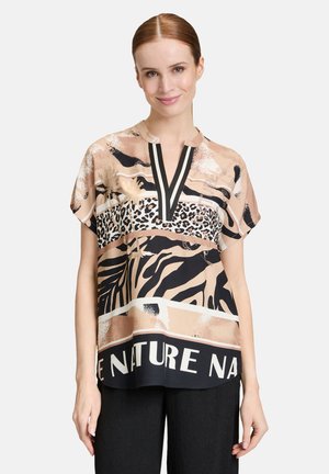Korte mouw blouse met een v-hals, voorzien van beige, zwarte en gouden abstracte patronen met dierenprint en vetgedrukte tekst aan de onderkant.