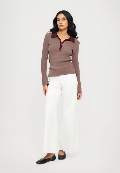 Maroon ribbed long-sleeve polo with a burgundy collar and three-button placket, paired with wide white trousers and black flats.