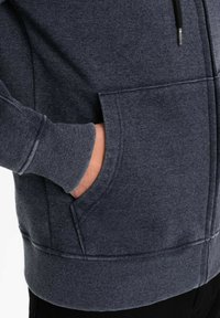 Felpa con zip di colore blu scuro, con una finitura testurizzata, tasche frontali, polsini e orlo a coste, dotata di un cordoncino al colletto per la regolazione.