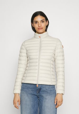 Lichtbeige pufferjack met een hoge kraag en ritssluiting, voorzien van horizontale quiltpatronen en een oranje accent op de rits.