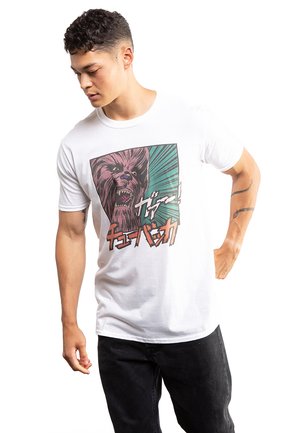 Weißes Baumwoll-T-Shirt mit einem Grafikdruck eines brüllenden Wesens in kräftigen Farben, vor einem Hintergrund mit grünen und roten Explosionseffekten.