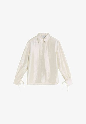 Elfenben, långärmad skjorta med en något glansig yta, knäppning fram och snören vid ärmarna. Har klassisk krage och avslappnad passform.