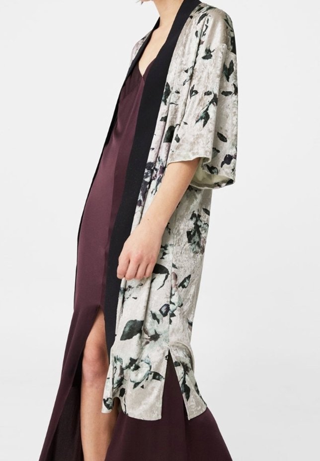 Długi żakiet w stylu kimono w jasnoszarym kolorze z kwiatowym wzorem, czarnymi akcentami i szerokimi rękawami, założony na głęboko burgundową sukienkę z rozcięciem.