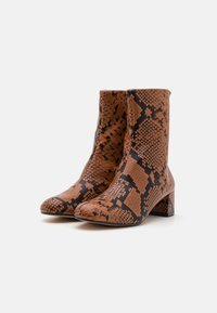 Botas de tobillo con estampado de serpiente en marrón y negro, con una puntera ligeramente puntiaguda y un tacón cuadrado, hechas de material sintético texturizado.