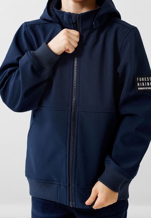 Granatowa bluza z zamkiem błyskawicznym, z kapturem, ściągaczami przy mankietach i u dołu. Posiada naszywkę z napisem "LEŚNE WĘDRÓWKI" na lewej piersi. Miękki, gładki materiał.