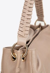Beżowa skórzana torebka z plecionym paskiem, złotymi akcentami i teksturowanym wykończeniem. Posiada okrągłe metalowe pierścienie przy punktach mocowania.