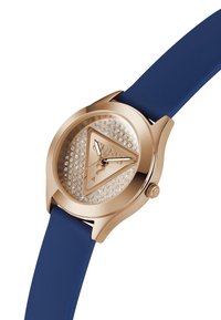 Reloj en tono dorado con caja redonda, correa de silicona azul, esfera triangular decorada con rhinestones y manecillas de horas y minutos sencillas.