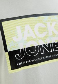 Grijze katoenen t-shirt met een grote grafische print. Het ontwerp bevat zwarte, witte en gele geometrische patronen met de tekst "JACK & JONES."