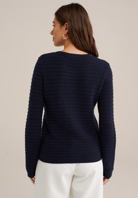 Navy knit sweater with textured horizontal stripes, crew neckline, and ribbed cuffs and hem. Standard fit, long sleeves, and soft fabric.
