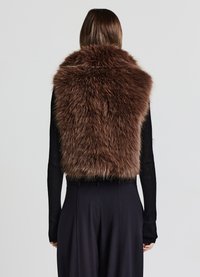 Braune Kunstpelzweste mit hohem Kragen, geschichteter Textur und taillierter Passform, kombiniert mit einem schwarzen, gerippten Langarmoberteil und dunklen Hosen.