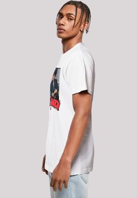 White cotton t-shirt featuring a large printed graphic of a man, with bold red text below. Short sleeves and standard fit.