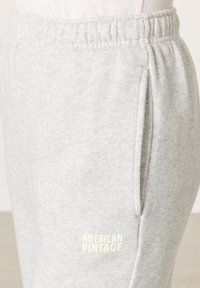 Sivé teplákové nohavice z mäkkej látky, s pásom na šnúrku, bočnými vreckami a malým bielym logom "AMERICAN VINTAGE" na nohavici.