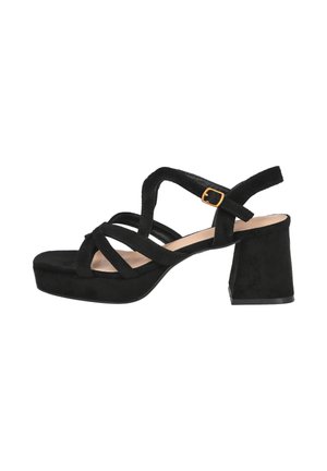 Sandal de mujer de ante negro con tacón cuadrado, tiras entrelazadas y una correa de tobillo con hebilla dorada, vista lateral sobre fondo blanco.