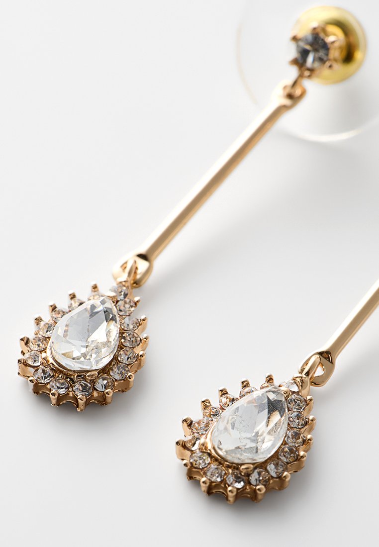 Orecchini a goccia color oro con una pietra chiara a forma di pera circondata da piccole pietre trasparenti, montati su un perno dritto.