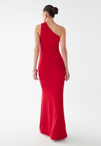Červené jednoramenné dlhé šaty vyrobené z hladkej látky. Tvarovo priliehavý dizajn s hladkým povrchom a minimálnymi akcentmi.