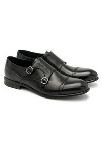 Zapatos de cuero negro con un diseño elegante, acentos de doble hebilla y perforaciones decorativas en las punteras. Textura suave y forma puntiaguda.