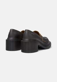 Scarpe nere in pelle con tacco a blocco, suola in gomma rigata e cuciture dettagliate. Presentano una punta arrotondata e un design slip-on.