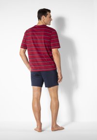Red and navy striped t-shirt with short sleeves, paired with navy shorts. Fabric appears soft with a relaxed fit. Barefoot orientation.