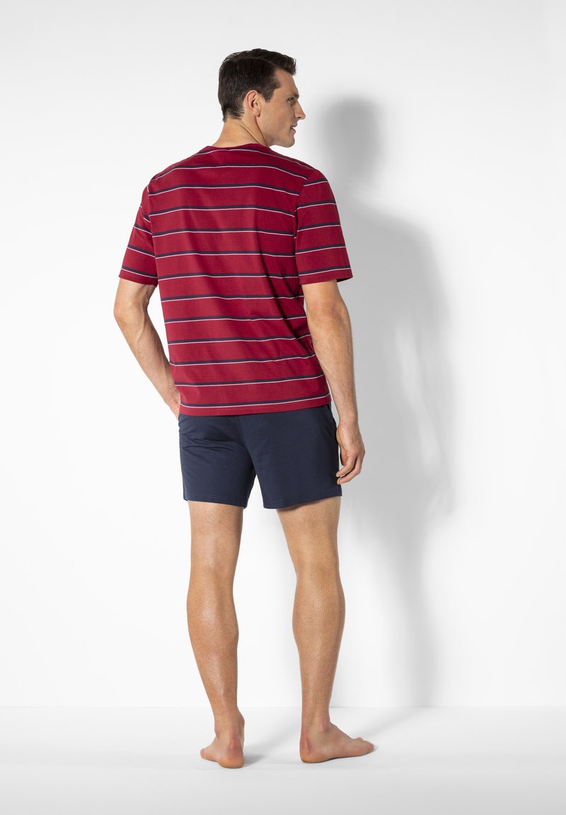 Red and navy striped t-shirt with short sleeves, paired with navy shorts. Fabric appears soft with a relaxed fit. Barefoot orientation.