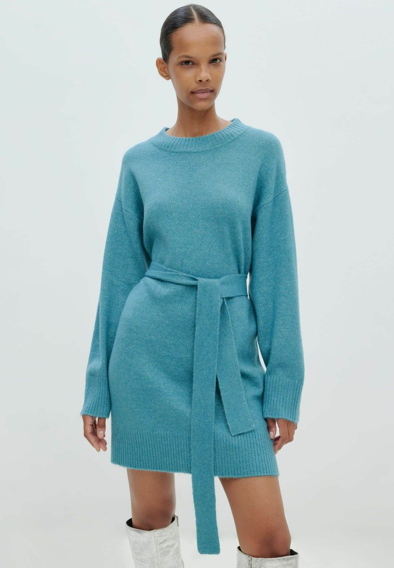 Türkises Strickkleid mit gerippten Bündchen und Saum, ausgestattet mit einem passenden Gürtel in der Taille. Weiche Textur, lässige Passform, lange Ärmel.
