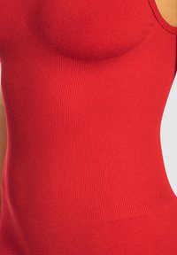 Body rojo acanalado con un diseño ajustado, fabricado en una tela suave y con un patrón ligeramente texturizado en la zona del busto.