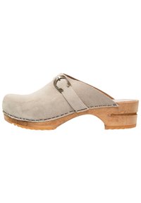 Beige Wildlederschuh mit Holzsohle, ausgestattet mit einer Metallbuckle-Akzentuierung. Glatte Textur, runde Zehenform und Nahtdetails entlang des Randes.