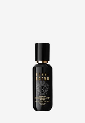 Bouteille noire avec du texte et des accents dorés. Possède une forme cylindrique et un capuchon rond. Le texte inclut le nom de la marque et les détails du produit.