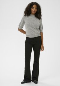 Haut gris à manches courtes en tissu tricoté, associé à un jean noir évasé. La tenue présente une silhouette ajustée et un design simple.