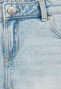 Helle blaue Jeansshorts mit sichtbarem Metallknopf, Kontrast-Nähten in goldenem Farbton und einem subtilen Texturmuster.