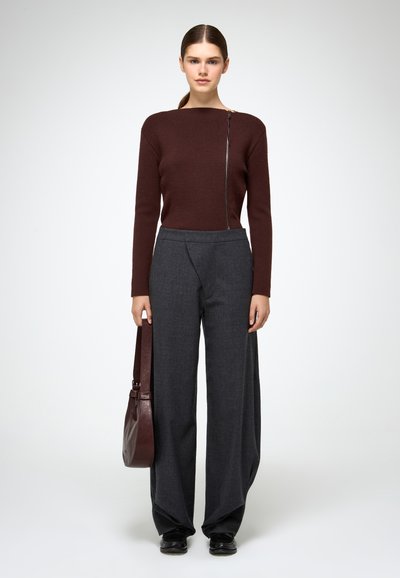 Burgundi pikkade varrukatega topp külgzipperiga, koos kõrge vöökoha ja laia säärega hallide pükstega. Mudel kannab tumepruuni õlakotti.