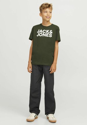 T-shirt in cotone verde con grande testo bianco "JACK & JONES", abbinato a pantaloni neri larghi e scarpe da ginnastica di colore chiaro.