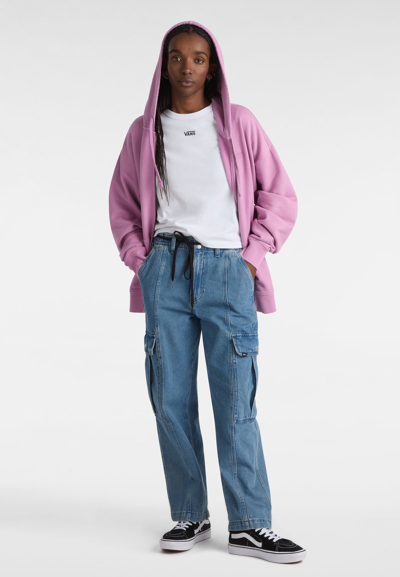 Rosa hættetrøje, hvid t-shirt med logo, blå cargo-bukser, sort og hvid sneakers. Afslappet outfit med løs pasform.