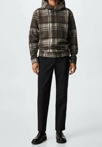 Sudadera con capucha de cuadros en marrón oscuro y gris, combinada con pantalones negros y botines. La tela es suave con una apariencia texturizada.