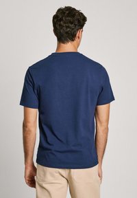 Temno moder kratek rokav T-shirt z okroglim izrezom, izdelan iz gladkega bombažnega blaga, z minimalnimi šivi in sproščenim krojem.