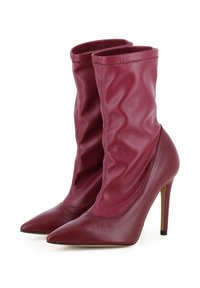 Bottes à talons hauts bordeaux avec un design loose, bouts pointus, texture en cuir lisse et détails de couture sur le bord supérieur.