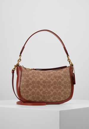 Sac à bandoulière marron et beige à motifs, de forme incurvée, avec garniture en cuir, ferrures dorées et bandoulière longue détachable, posé sur un socle blanc.