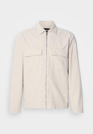 Light beige corduroy jacket with a front zipper, two chest pockets, a collar, and long sleeves. Smooth texture and a minimalist design.