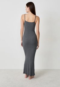 Vestido maxi de canalé gris con tirantes delgados ajustables, silueta ajustada y tejido texturizado que llega hasta el suelo.