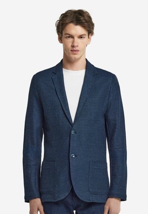 Navy blue blazer made of textured fabric, featuring two buttons, notched lapels, and two front pockets, worn over a white shirt.
