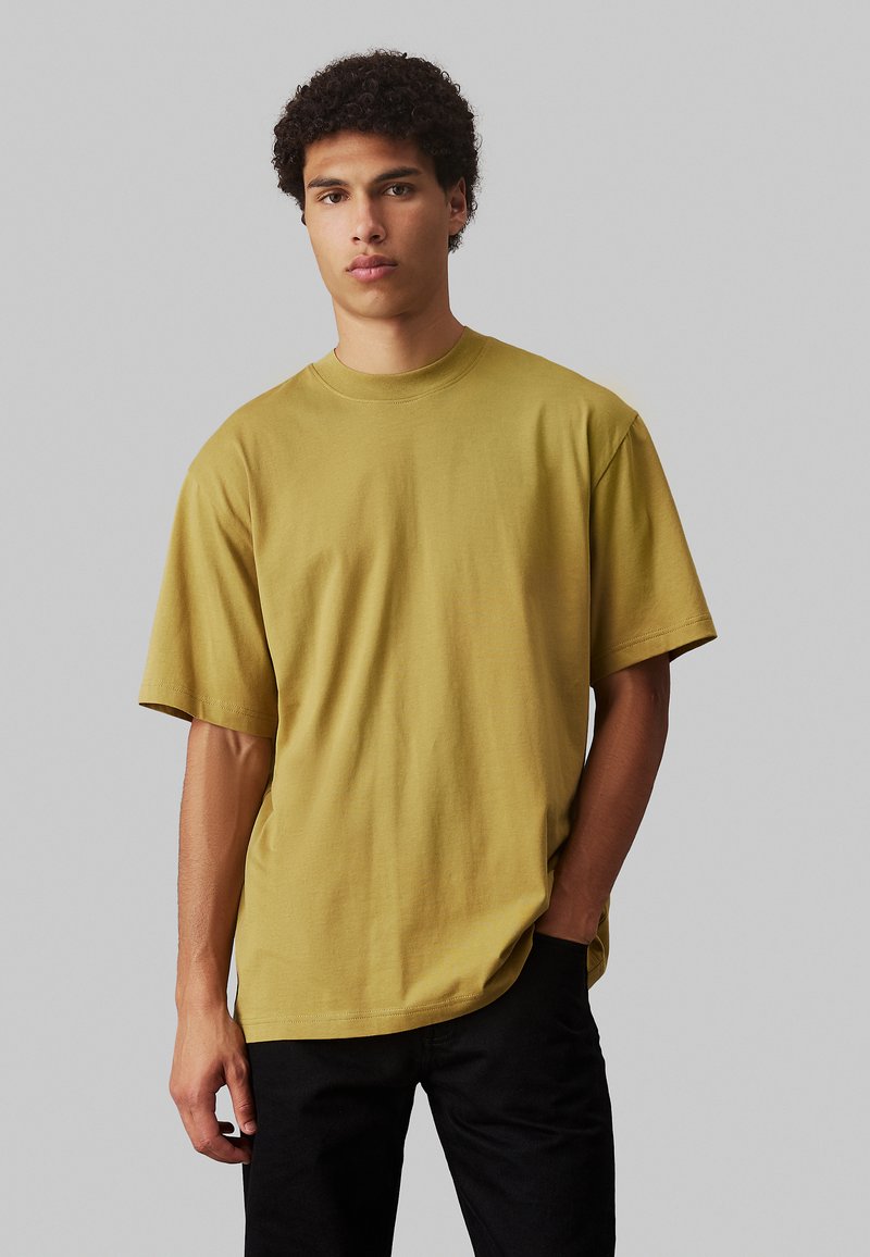 T-shirt a maniche corte giallo senape con vestibilità rilassata, realizzato in cotone, con una superficie liscia e design a girocollo.
