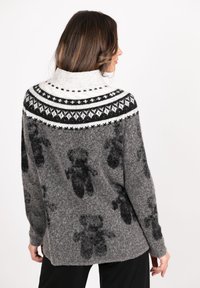 Gray knit sweater with a high collar, featuring a black and white geometric pattern along the shoulders and teddy bear motifs throughout.