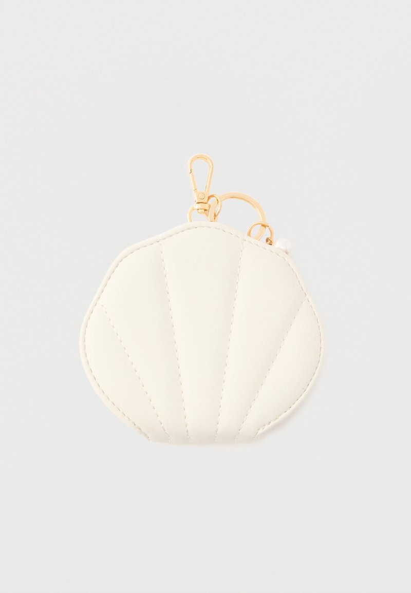 Petit porte-monnaie en forme de coquillage couleur crème avec anneau porte-clés doré et fermoir mousqueton sur fond uni.