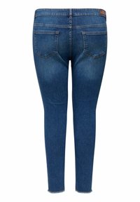 Jean skinny en denim délavé moyen, avec taille haute, deux poches arrière et ourlet effiloché. Texture lisse avec des détails de décoloration légère.