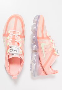Zapatillas deportivas ligeras y translúcidas de color rosa con una parte superior de malla, lengüeta acolchada y cápsulas de amortiguación visibles en la suela. Presentan detalles en color verde.