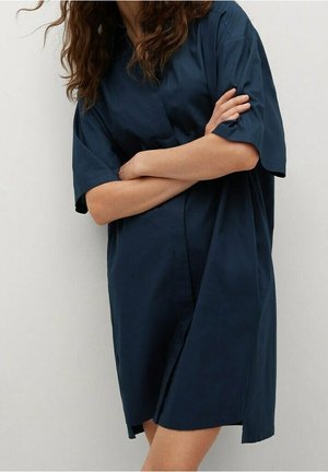 Marineblå skjortekjole med korte ærmer i en afslappet pasform. Den har knapper foran, krave og en glat, let stoftekstur.