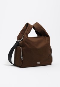 Brązowa torba na ramię z tkaniny o teksturowanej powierzchni, z górnym uchwytem i regulowanym czarnym paskiem. Posiada dwie boczne kieszenie na zamek oraz logo.