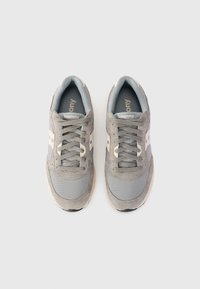 Scarpe da ginnastica grigie realizzate con una combinazione di materiali scamosciati e in rete, caratterizzate da accenti bianco sporco, una superficie texturizzata e una forma arrotondata.