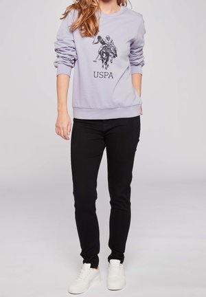Light purple sweatshirt featuring a black polo player graphic and "USPA" text, paired with black slim-fit pants and white sneakers.